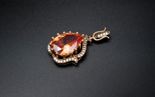 Gold pendant with a red gemstone on a black background