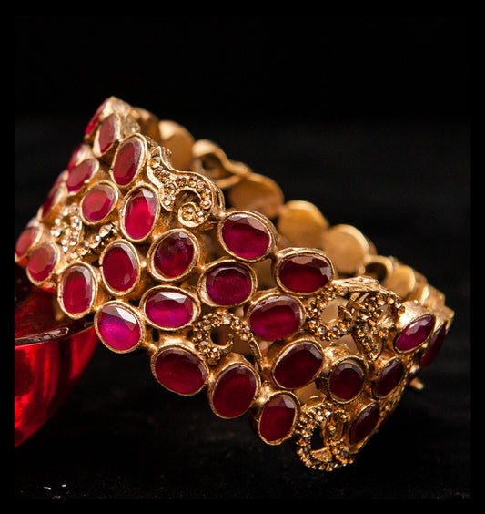 Gold bracelet with red stones on a black background