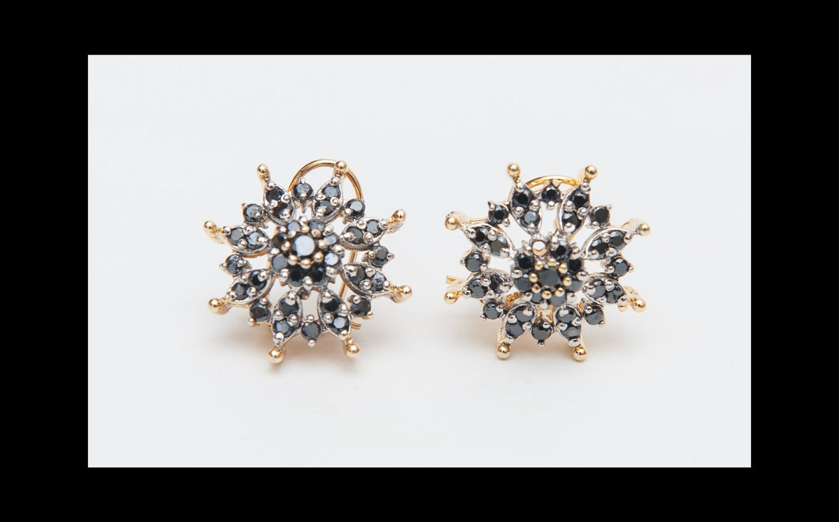 Pair of gold and black stud earrings on a white background