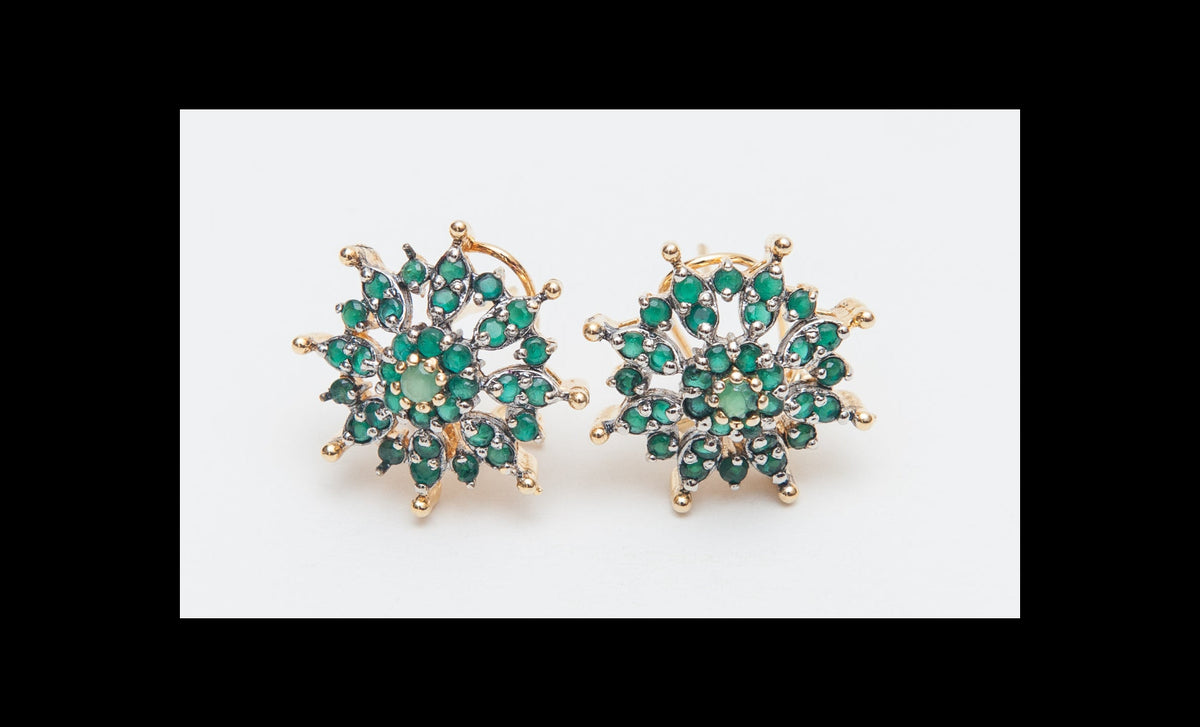Pair of gold earrings with green gemstones on a white background