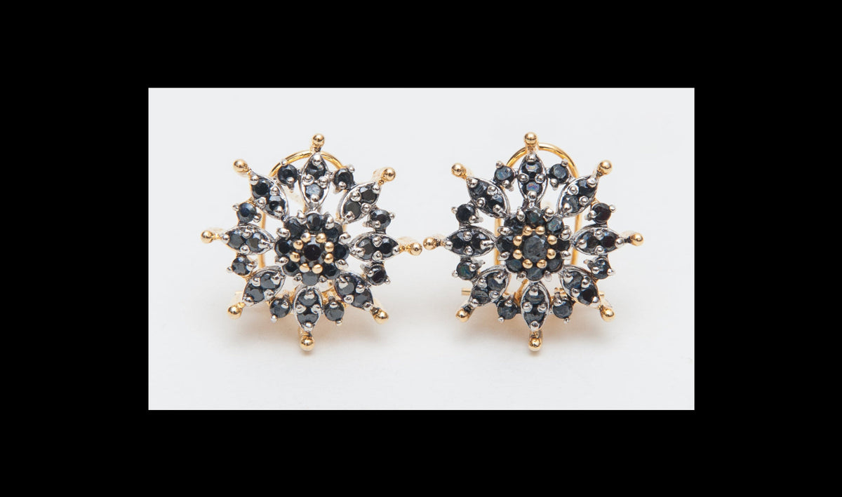 Gold and black snowflake-shaped earrings on a white background
