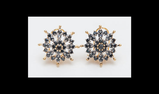 Gold and black snowflake-shaped earrings on a white background