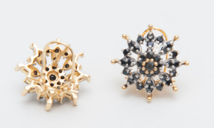 Pair of gold and black stud earrings on a light gray background