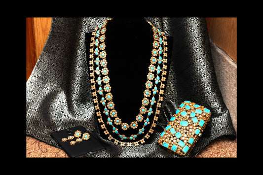 Jewelry set with necklace, earrings, and phone case on a textured surface