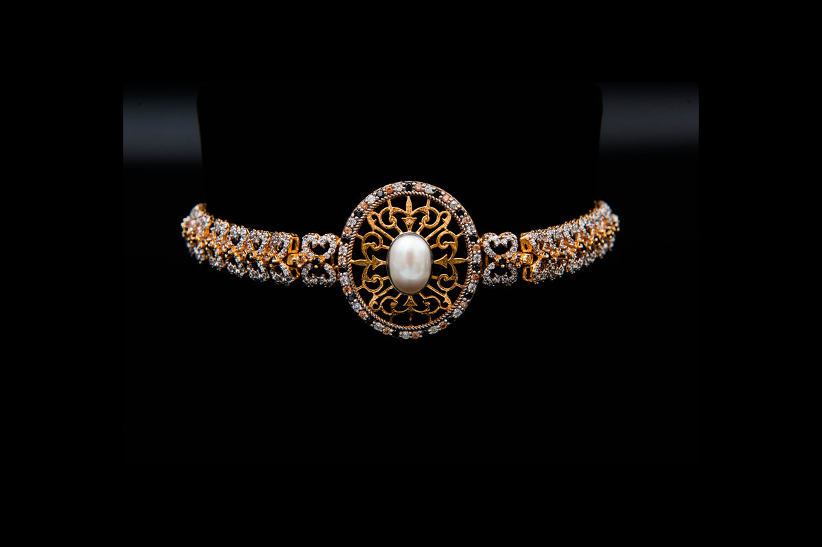 Gold and diamond bracelet with a central pearl on a black background