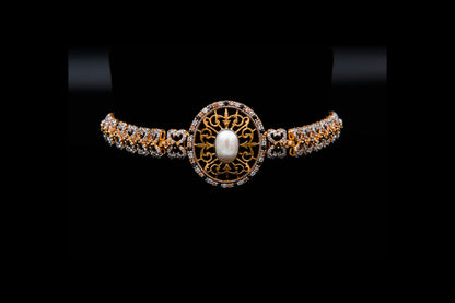 Gold and diamond bracelet with a central pearl on a black background