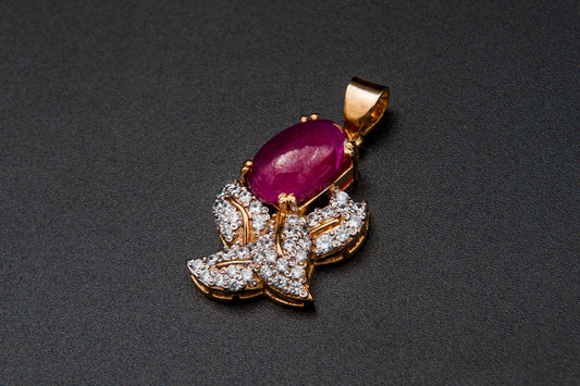 Jewelry pendant with a red gemstone and diamond accents on a dark background