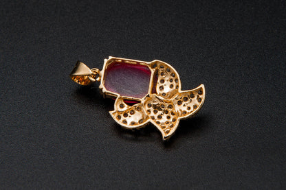 Gold pendant with a red gemstone on a black background