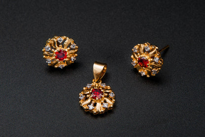 Gold jewelry set with a pendant and two earrings on a black background