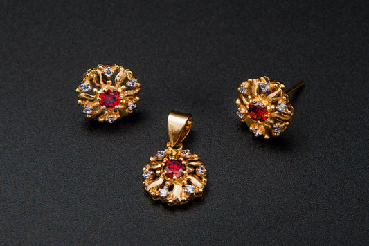 Gold jewelry set with a pendant and two earrings on a black background