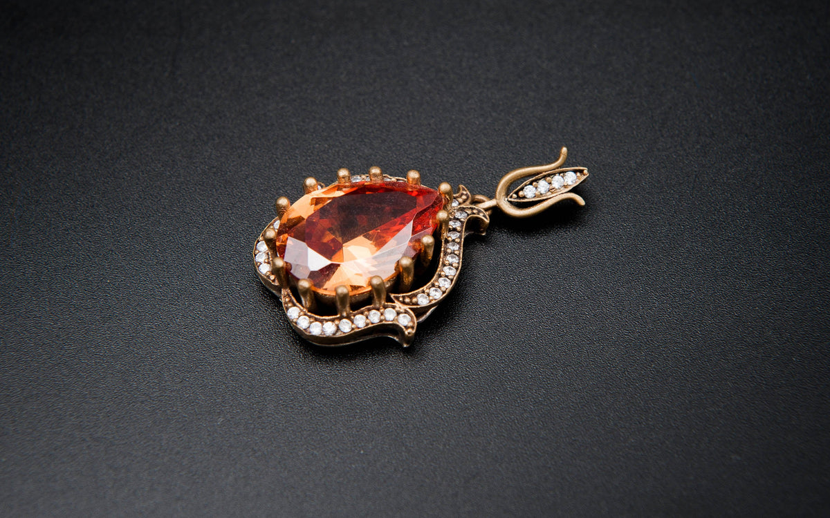 Gold pendant with a red gemstone on a black background
