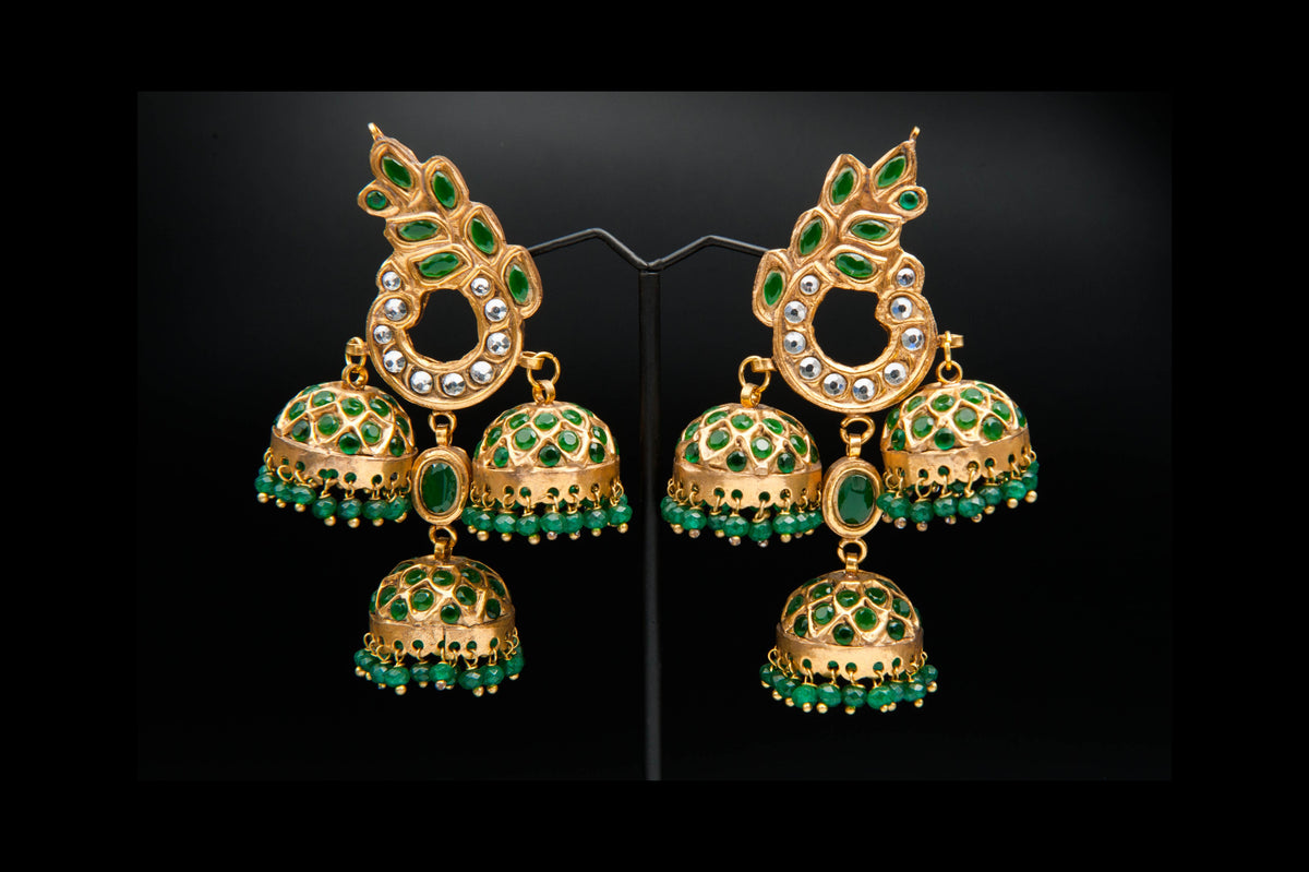 Gold and green gemstone earrings on a black background