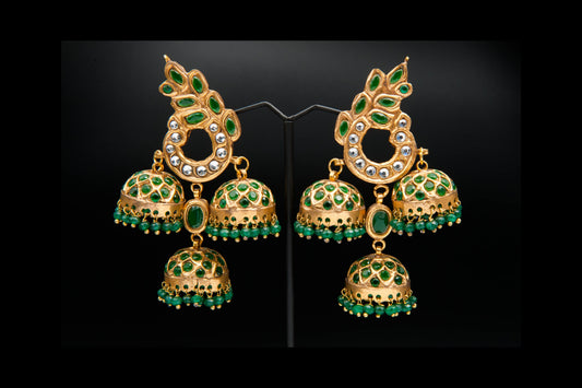 Gold and green gemstone earrings on a black background