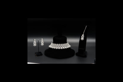 Jewelry set including a necklace and earrings on black stands against a dark background