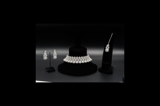Jewelry set including a necklace and earrings on black stands against a dark background