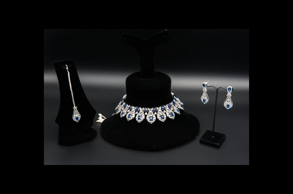 Jewelry set including necklace, earrings, and pendant on black stands against a dark background