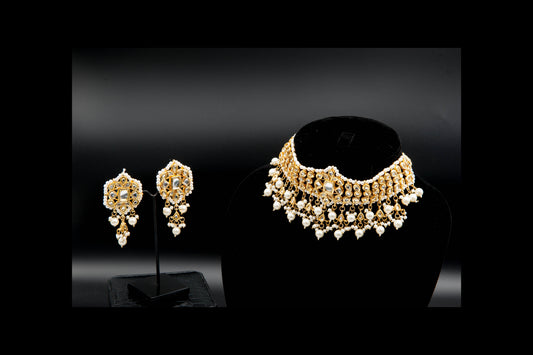 Gold necklace and earrings on black stands against a dark background