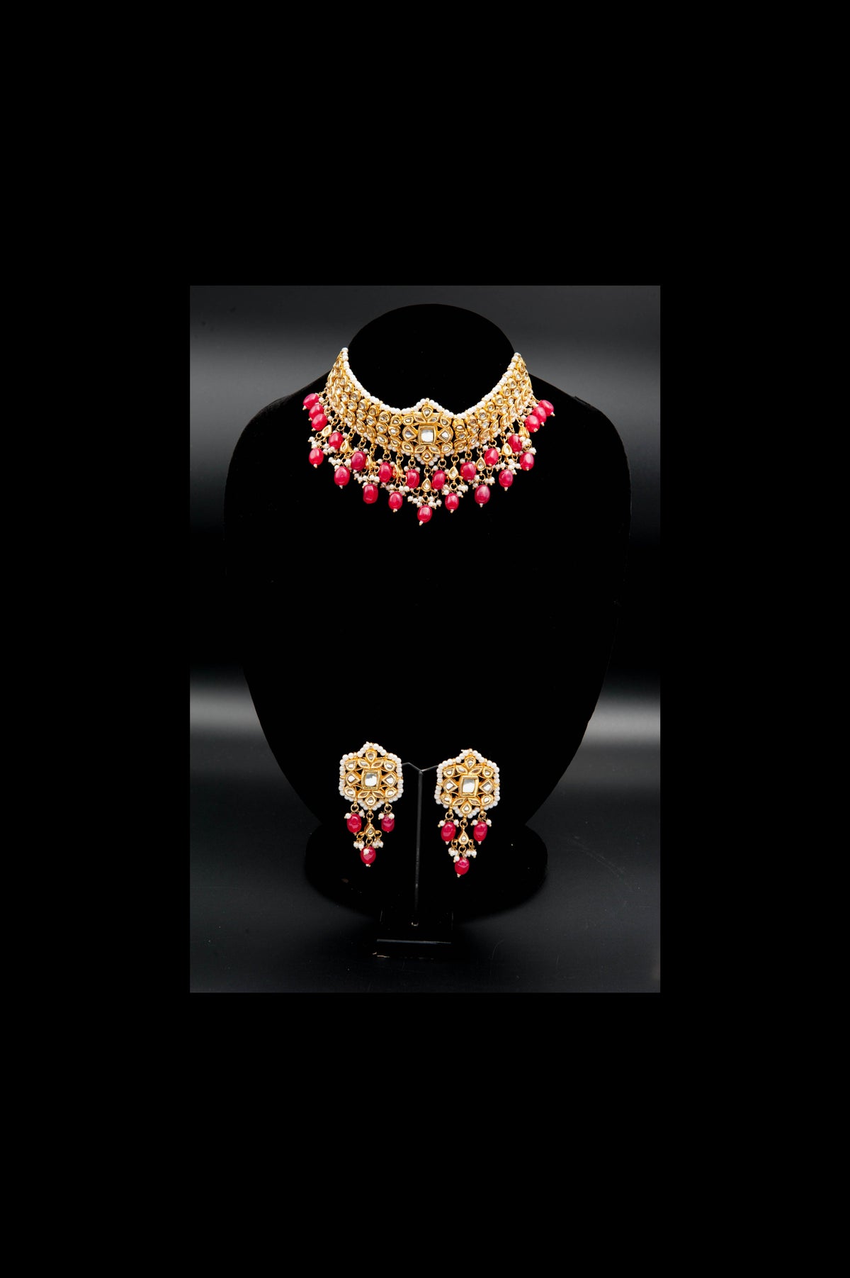 Gold and pink jewelry set on a black stand